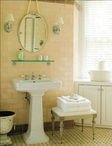 erik-johnson-bath-subway-tile-off-white-wall-oval-vanity-mirror-chrome-sconces-shades-pedestal-sink-urn-hex-dot-tile-floor-louis-style-bench-seat-glass-shelf