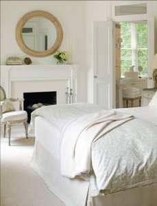 erik-johnson-bedroom-white-bed-linens-louis-armchair-chair-fireplace-mantel-natural-wood-round-mirror-carpet-rug-box-pleat-skirt